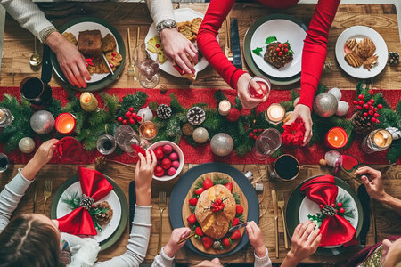 A festive Christmas dinner table with elegant glassware, plates, and a centerpiece of greenery and candles, ready for a holiday feast.の素材