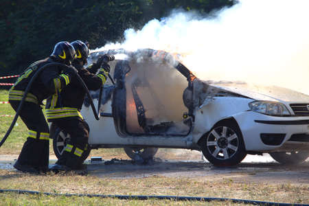 Demonstration switching off a car in flames by the Italian firefighters volunteers. Demonstration held in June 2015 in the province of Turin in Piedmont Italyの写真素材