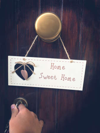 Home sweet Home Girl opens the door, plaque Home Sweet Home on the handle.の写真素材