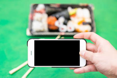 Bowl of sushi photographed by smartphone. Smartphone with darck screen, possible text space の写真素材