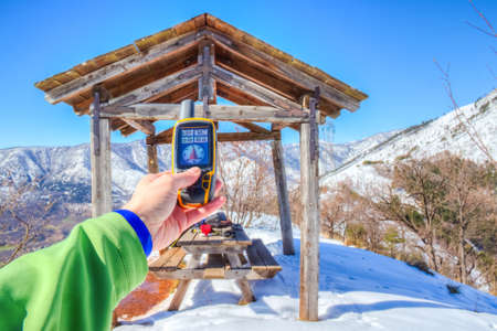 Snowy mountain panorama, hand holding an GPS receiver.の写真素材