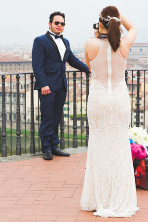 March 16, 2017- Florence Italy: Spouses take pictures of each other, a view of Florence in the background.のeditorial素材