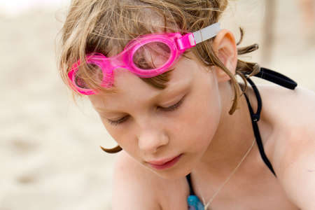 Sad girl in swimming goggles at the beachの写真素材
