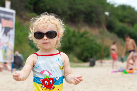 Adorable blonde curly hair little girl in fashionable sunglassesの写真素材