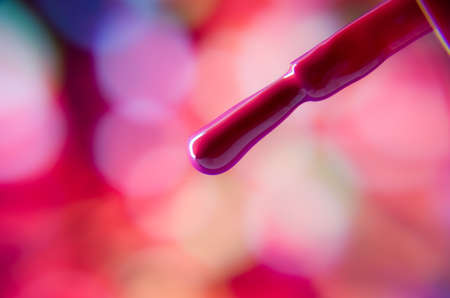 Close up of a red nail-polish brush against colorful backgroundのeditorial素材