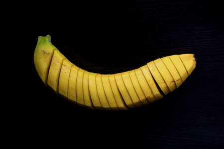 detail od a sliced banana including the yellow skin against black background