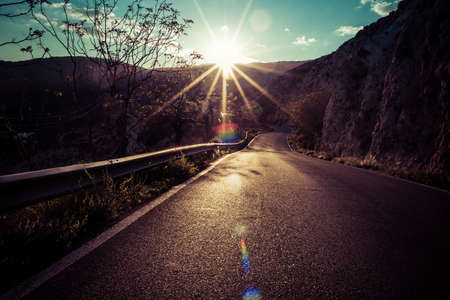 mountain road with the evening sun in frontの写真素材