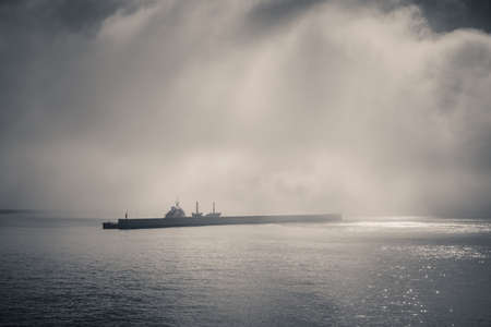 fog on the sea entering the port, covering a merchant shipの写真素材