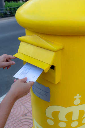 Aguadulce, Spain; September 27th 2021: Hands of woman throwing a letter in a yellow mailboxのeditorial素材
