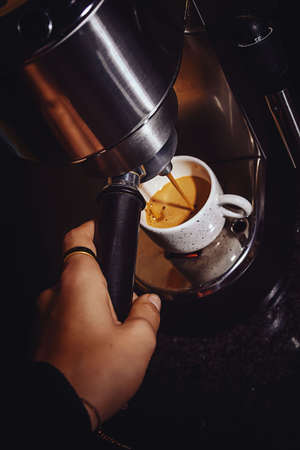 waitress hand preparing a professional espresso coffee from a machineの写真素材