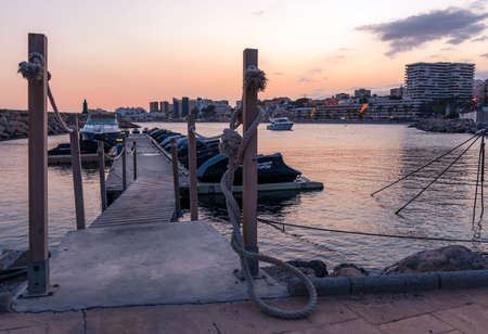 Aguadulce, Spain; September 19th 2021: recreational pleasure boat entering the harbor next to the jet ski pontoon, with the city skyline in the background at sunset.のeditorial素材