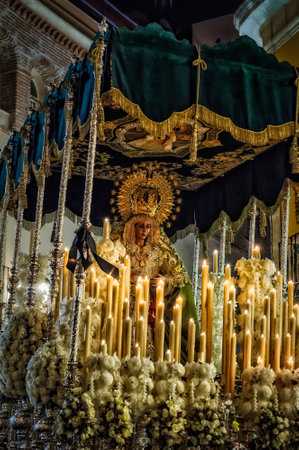 The Virgin of the Holy Mary of Hope Macarena on her throne during a Holy Week parade with the candles lit.の写真素材