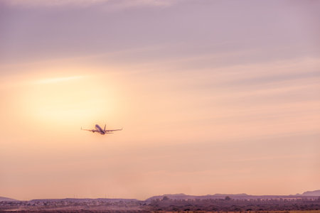 plane taking off, rising towards the sunrise sun. Holidays and travelの写真素材