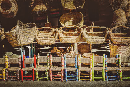 Handicraft articles made of esparto grass and children's chairs painted with colors and flowers in a craft and souvenir shop.の写真素材