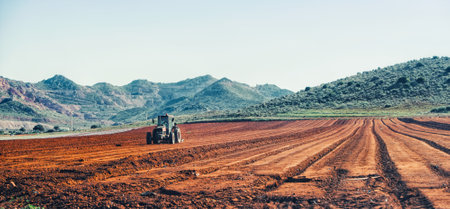 Tractor of farmer plowing the furrow field before planting.の写真素材