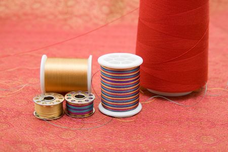 Closeup of spools and bobbin with thread on fabric
