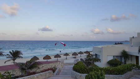 Evening flight of motorized parasailer above white sand beach La Isla Dorado Cancun Mexicoのeditorial素材