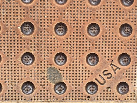 Weathered street steel cover plate with three letters reading USAの写真素材