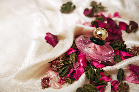 glass perfume bottle with dry plants on the light fabricの写真素材