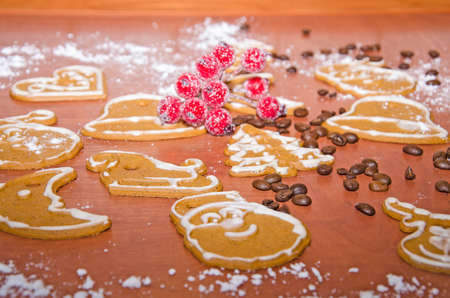 Christmas gingerbreads with white frosting, coffee beans and rowan twig for decoration on a wooden...