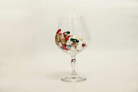 pills in wine glass on white backgroundの写真素材