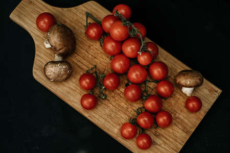 Champignons mushrooms and cherry tomatoes on a wooden background, flat lay, top viewの写真素材