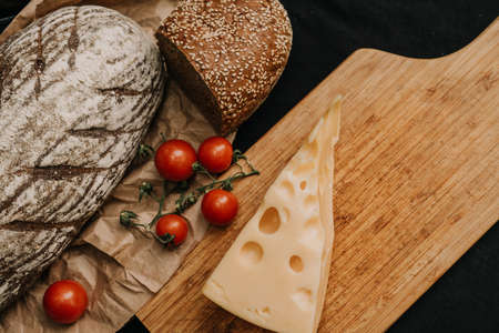 Fresh bread, cherry tomatoes, cheese on wooden backgroundの写真素材