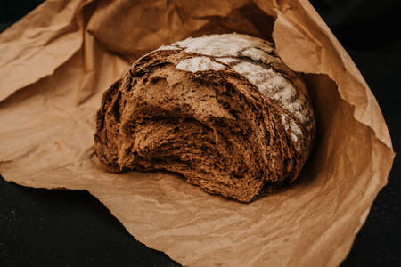 Fresh bread on paper on wooden black backgroundの写真素材