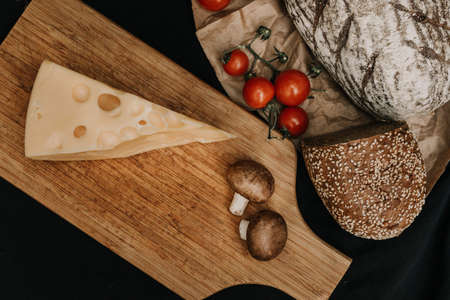 Champignons mushrooms, cherry tomatoes bread and cheese on black background, flat lay, top view