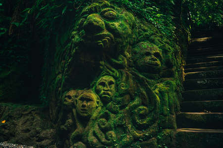 Beautiful carving faces with growing moss in Baliの写真素材