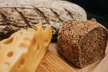 Fresh bread and cheese on paper on wooden black backgroundの写真素材
