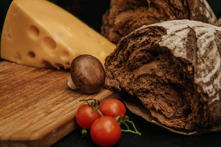 Champignons mushrooms, cherry tomatoes bread and cheese on black background, flat lay, top viewの写真素材