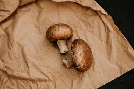 Champignons mushrooms on paper on black background, flat lay, top viewの写真素材