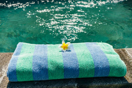 Blue towel and franjipani flower near swimming poolの写真素材
