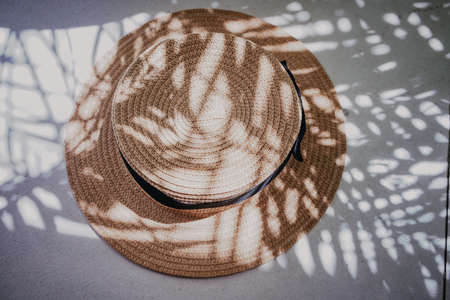 Summer straw hat through shadows of palm tree branchesの写真素材