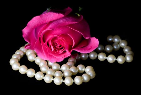 Closeup of pink rose and string of pearls on a black backgroundの写真素材