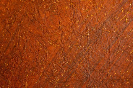 Background of crushed deep reddish brown paper with tiny flecks of goldの写真素材