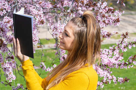 Young woman reading a book in the air with flowers