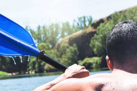 Detail of adult man doing a water sport in the air in a river by canoe as a healthy lifestyle