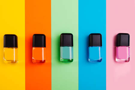 Group of vivid color nail polishes isolated on colorful backgroundの写真素材