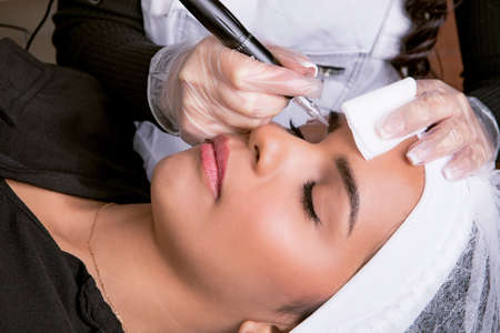 Beauticians hands, performing permanent eyebrow make-up. Microblading concept . High quality photo