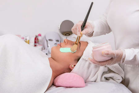 hands of Esthetician applying mask for facial cleansing treatment, skin care concept, close-up...