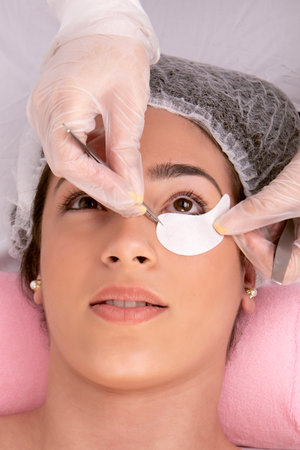 Beautician applying eye shield to proceed with the application of false eyelashes on the lower part of the eye of her client. High quality photoの写真素材