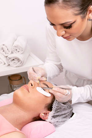 Beautician applying false eyelashes to her customer. High quality photo