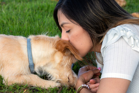 portrait of Young girl lying in the field and kissing her dog. High quality photos