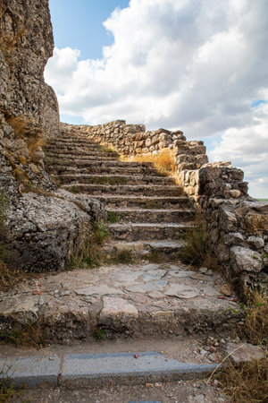 Visitors can see the well-preserved stone steps leading up to Atienza castle in Guadalajara, Spain, surrounded by rocky terrain and lush greenery. The scenery is a blend of history and nature.の写真素材