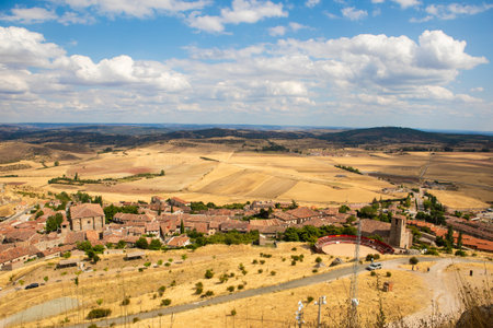 A picturesque view of the rolling hills surrounding Atienza, Guadalajara, Spain shows ancient ruins and grassy terrain under a bright sky, perfect for outdoor exploration and photography.の写真素材