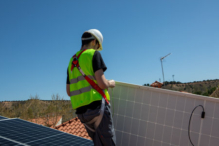 Solar panel installation on a residential roof under clear blue sky in mid-afternoonの写真素材