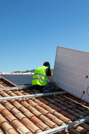 Solar panel installation on a residential roof under clear blue sky in mid-afternoon