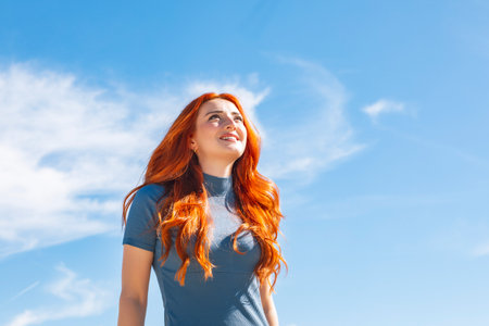 Young woman smiling looking at the sky with copy space on an urban street. High quality photo